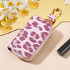 A pink leopard print car key holder with a gold clasp resting on a light background.