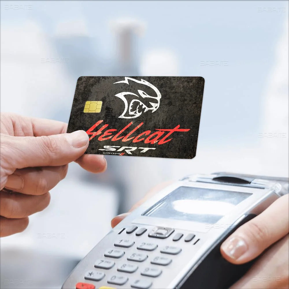 A hand holds an SRT Hellcat Demon Dodge card sticker film against a light background.