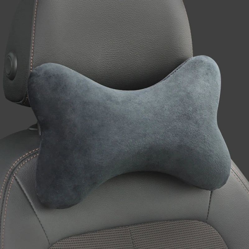 A gray memory foam car neck pillow resting on a dark automotive seat.
