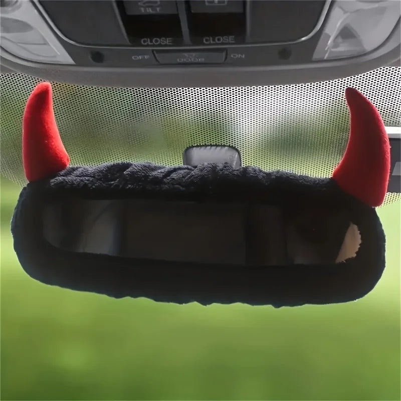 Décoration noire et poilue avec des cornes de diable rouges sur une cache-miroir de voiture.