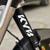 Close-up of a black motorcycle suspension fork with white KYB decals on the lower shaft.
