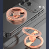 A close-up of a rose gold magnetic phone ring stand with a dual-sided grip resting on a smartphone.