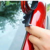 Eine Hand trägt einen schwarzen Scheibenabdeckstreifen auf den roten Rahmen eines Autos.