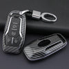 A carbon fiber style key fob cover with a metal chain is shown against a dark background.