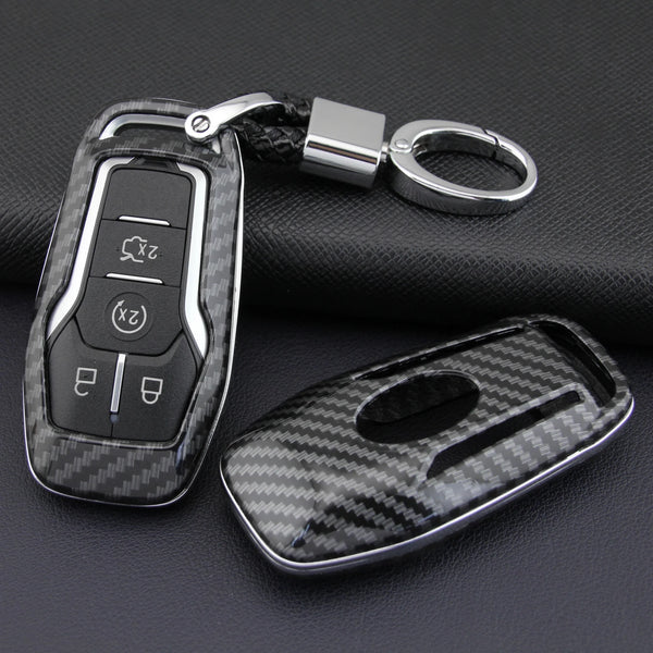 A carbon fiber style key fob cover with a metal chain is shown against a dark background.