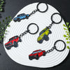 Four classic alloy car keychains in red, blue, yellow, and black are displayed on a white plate.