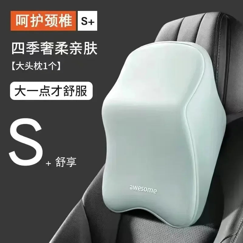 A light gray ergonomic car headrest cushion with a smooth, contoured shape is shown placed on a dark gray car seat.