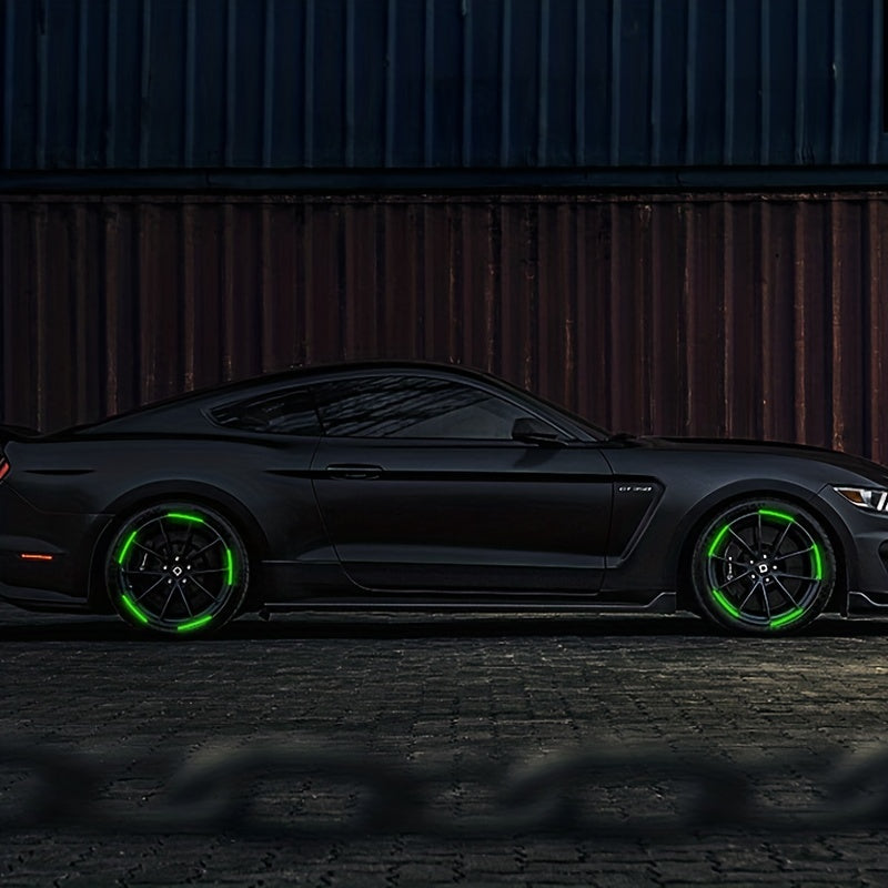 A dark gray sports car with bright green reflective wheel decals parked on a rough ground.