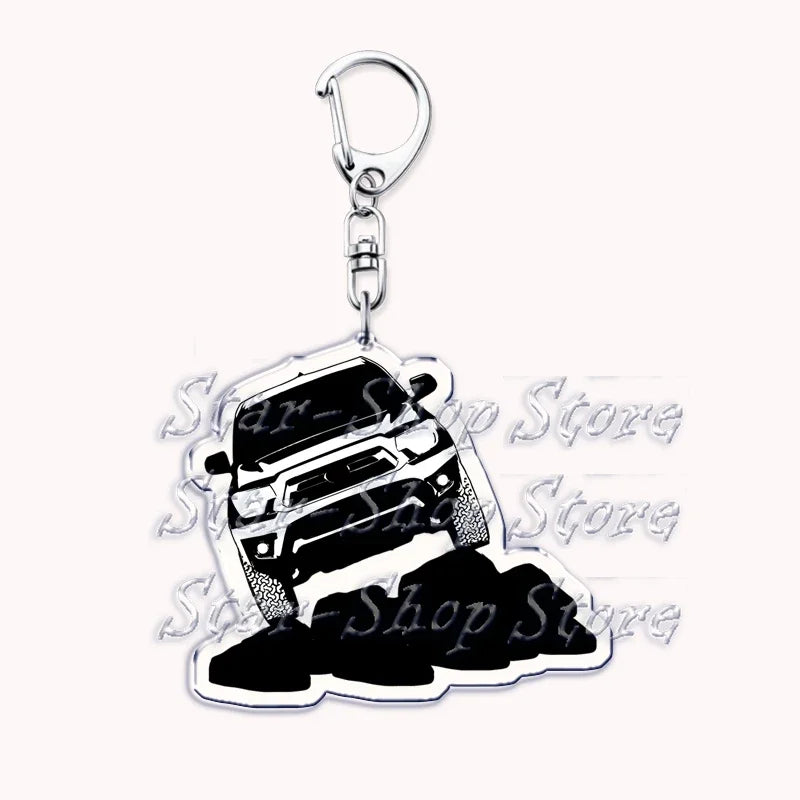 Silver acrylic keychain featuring a silhouette of an off-road truck on top of a pile of black rocks.