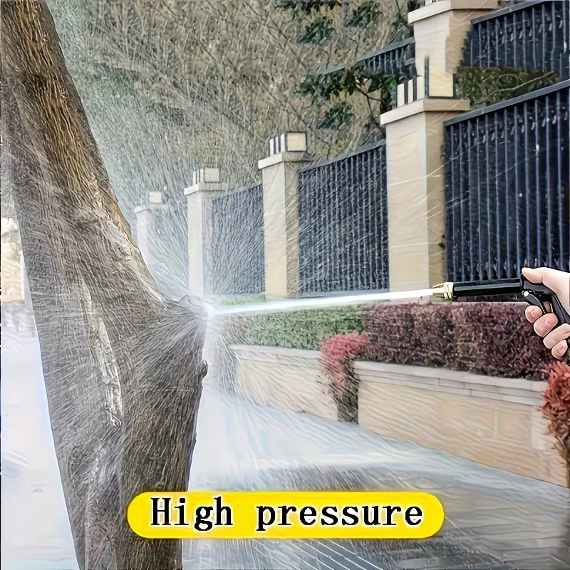A hand sprays a powerful stream of water from a high-pressure cleaning gun onto a tree trunk and garden area.