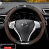 Close-up of a Nissan steering wheel with a carbon fiber patterned leather cover.