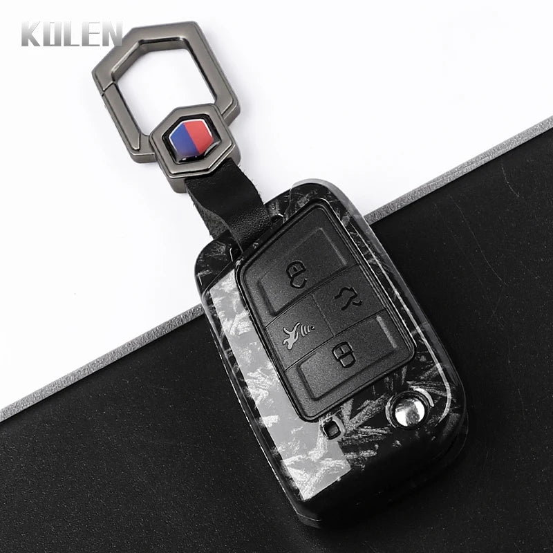 A black carbon fiber button cover for a car key, featuring a silver clip and colored accent.