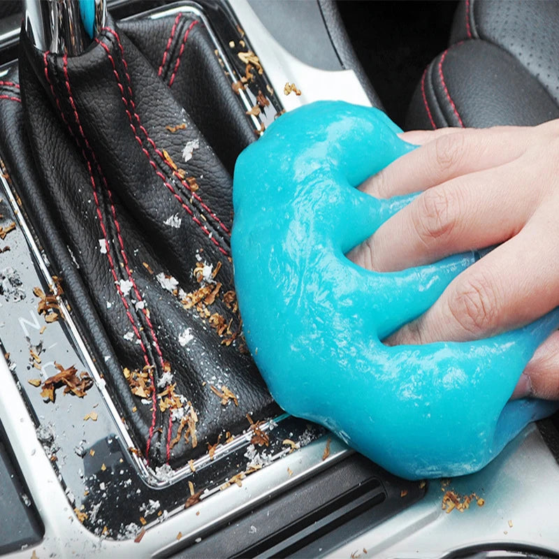 A hand applies bright blue magic gel cleaner to a car surface or household item.