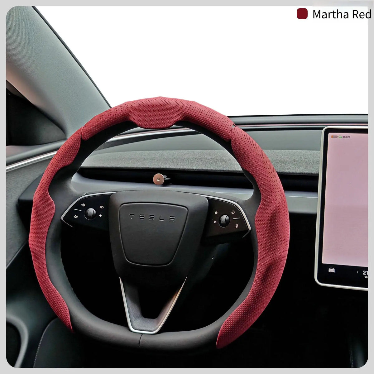 A close-up view of a red breathable perforated leather steering wheel cover for a Tesla vehicle.