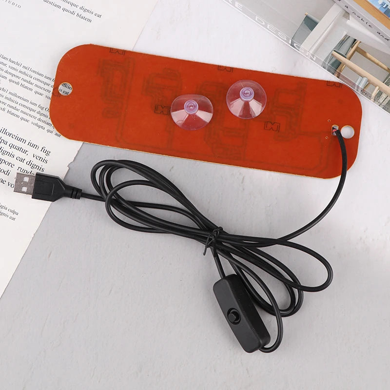 Dispositivo electrónico naranja con tres lentes rojas translúcidas y un cable negro, probablemente una lámpara de señalizació