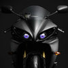 Close-up of a black motorcycle headlight featuring striking purple LED eyes.