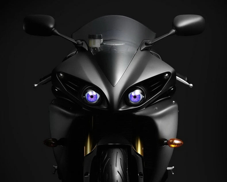 Close-up of a black motorcycle headlight featuring striking purple LED eyes.