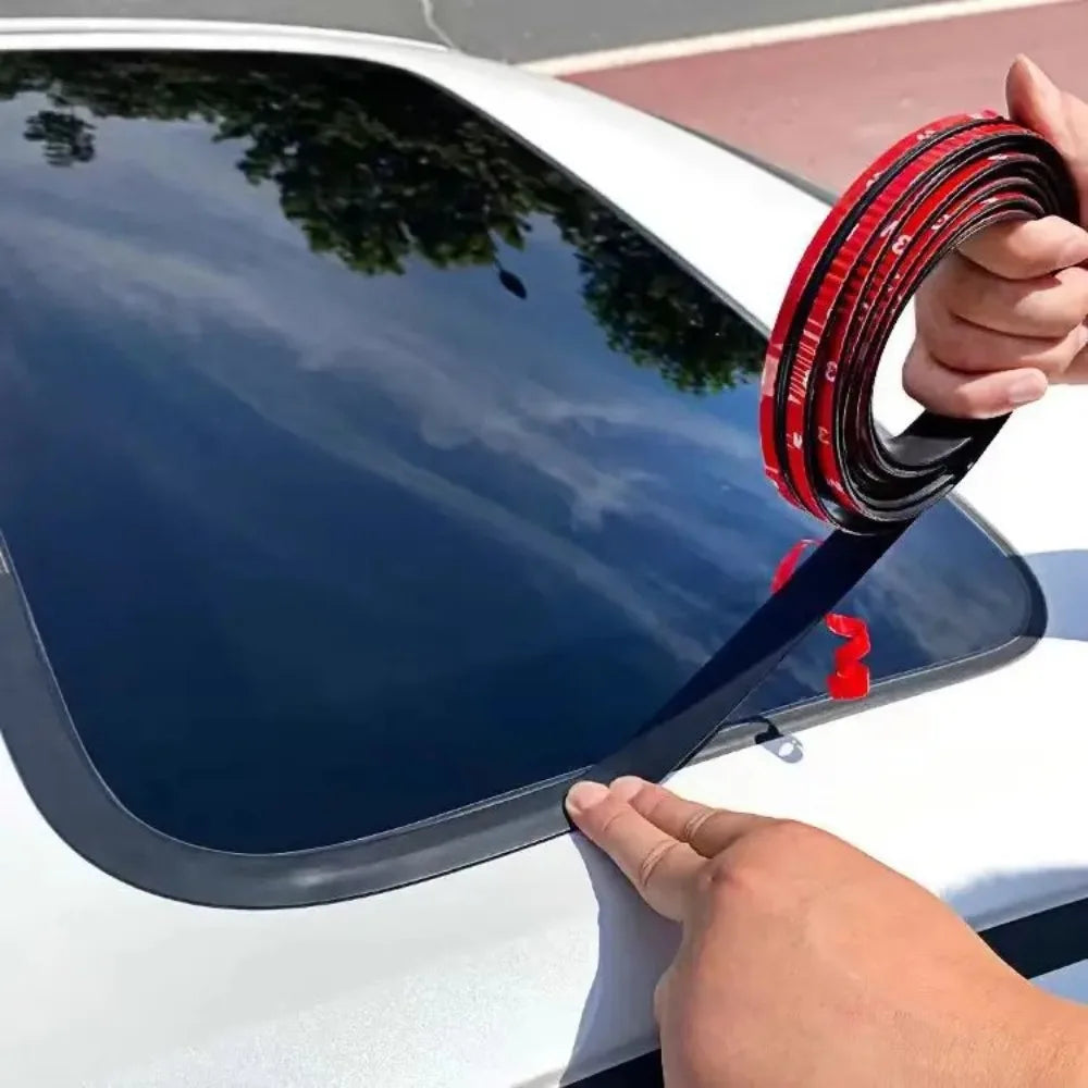 Una mano está instalando una tira de goma negra para el espacio de una ventana de un vehículo.