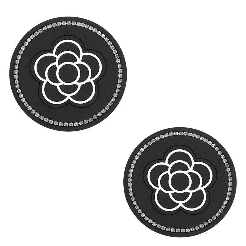 A set of two black silicone car cup coasters featuring a white floral design.