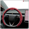 A close-up view of a red steering wheel cover on a car's steering wheel.