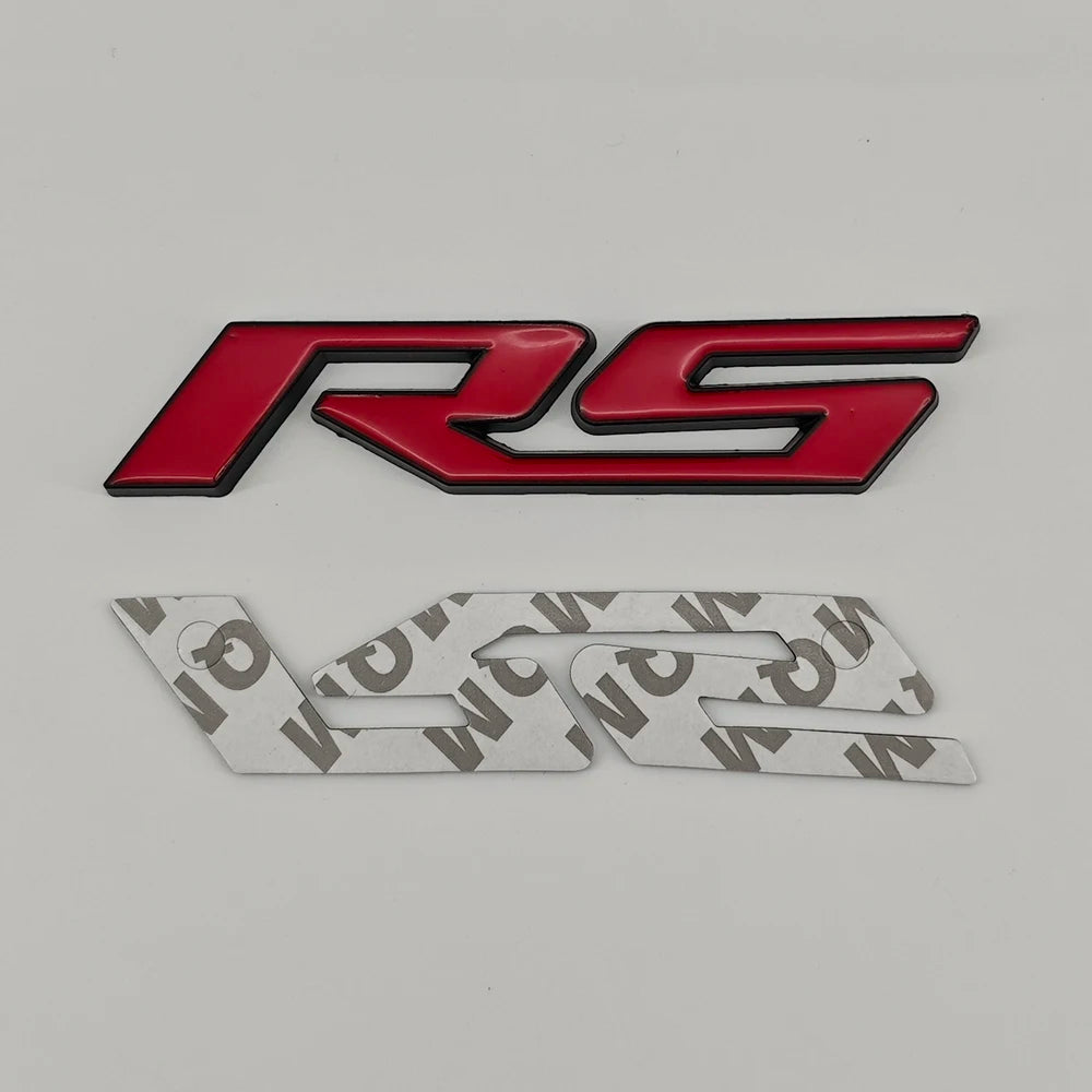 A red and black RS emblem badge for Chevrolet vehicles, shown alongside a silver version.