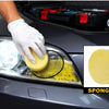 A gloved hand applies yellow sponge cleaning paste to a car headlight lens.