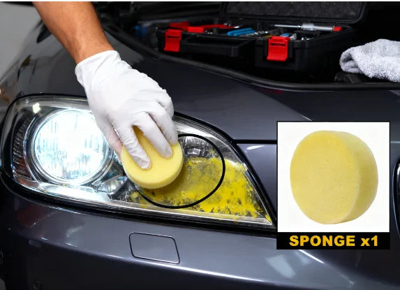 A gloved hand applies yellow sponge cleaning paste to a car headlight lens.