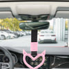 A pink heart-shaped handle accessory is shown attached to a rearview mirror mount inside a car.