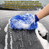 A hand wearing a blue microfiber car wash mitt is washing a car surface covered in water and soap foam.