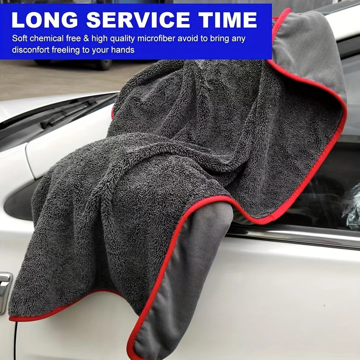 A dark gray microfiber drying towel is shown draped over the open door of a white car.
