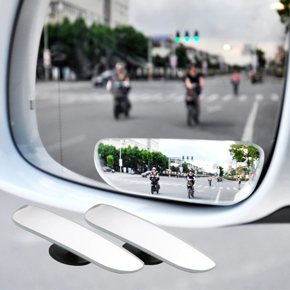 A convex angle car mirror reflecting a street scene and surrounding environment.