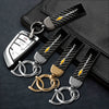 A set of luxury metal car keyrings with black leather straps and silver and gold split rings displayed on a dark surface.