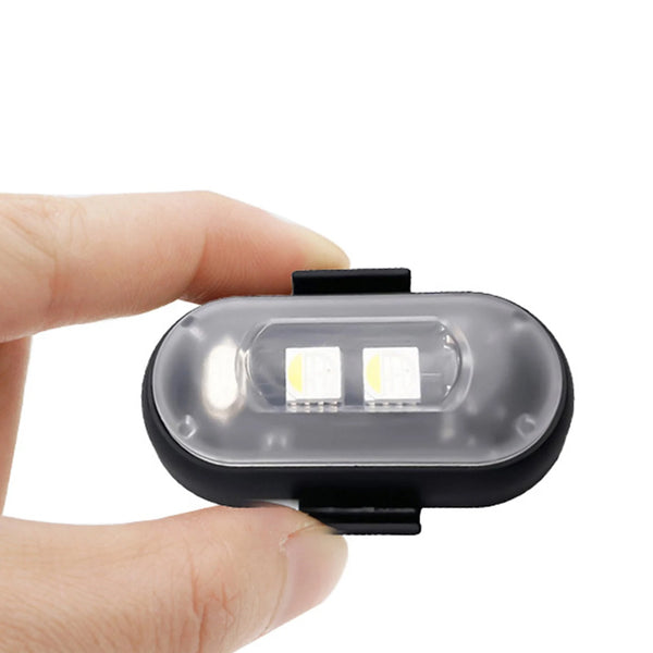 Una mano sostiene una luz estroboscópica LED inalámbrica negra con dos LEDs blancos brillantes internos.