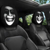 Two black car headrest covers featuring stylized, grinning horror faces are shown inside a vehicle.