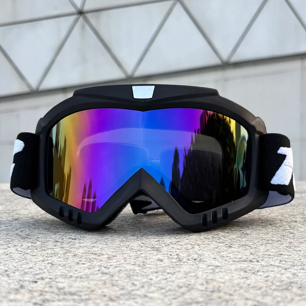A pair of black windproof sports goggles with purple and blue mirrored lenses resting on a gray surface.