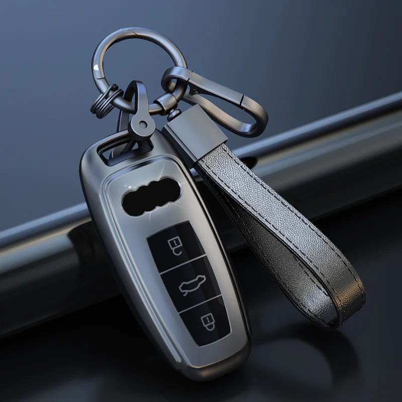 A silver car key fob attached to a black leather strap and keyring.