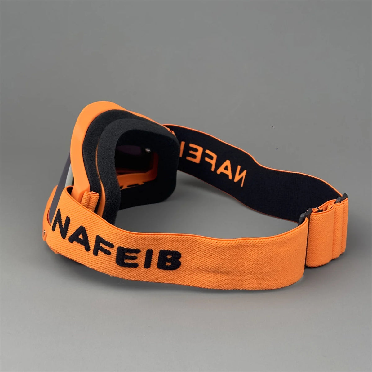 Orange and black off-road racing goggles with an adjustable strap displayed on a gray background.