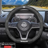 Close-up view of a black Nissan steering wheel with carbon fiber trim and instrument cluster.