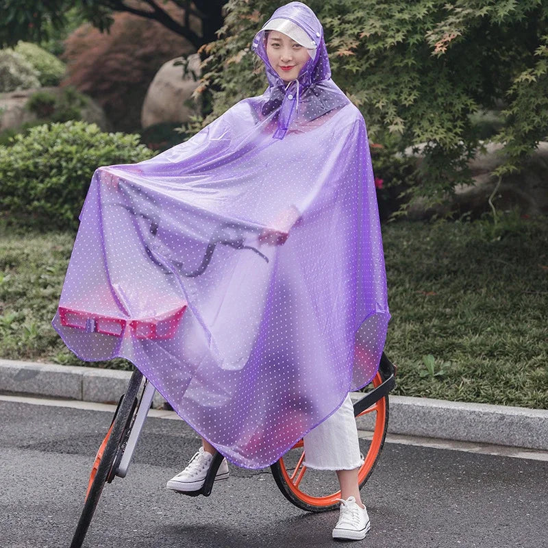 A woman wearing a purple transparent windproof motorcycle rain poncho is standing next to a bicycle in an outdoor setting.