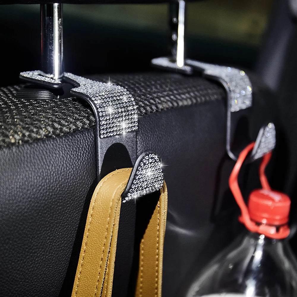 Close-up of dual artificial diamond car hooks attached to a black storage bag or item.