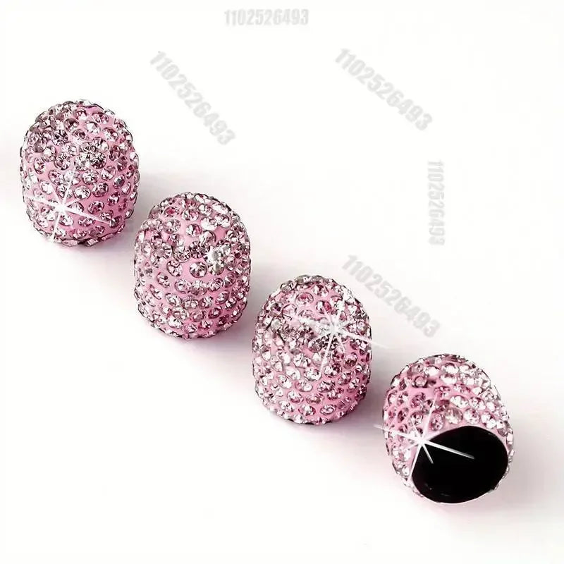A set of pink crystal diamond finish tire valve caps arranged diagonally on a white background.