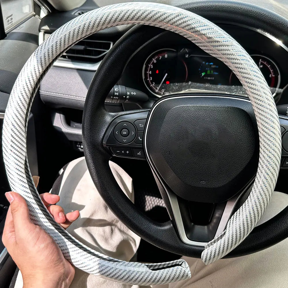 Eine Hand hält eine universelle Kohlefaser-Lenkradabdeckung im Auto-Cockpit.