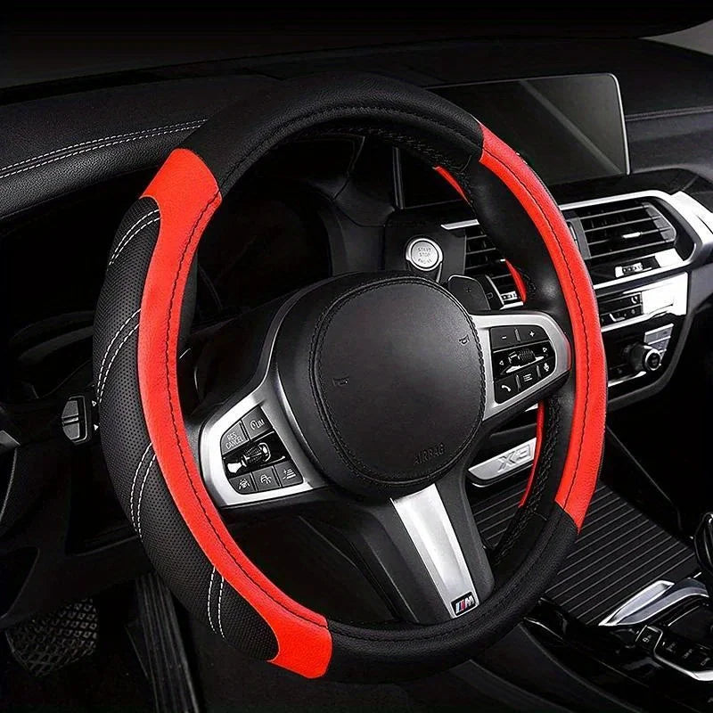 A black steering wheel with an orange accent rim and silver controls inside a car interior.