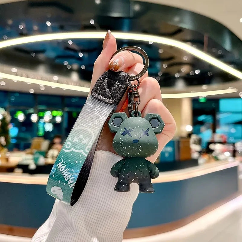 Une main tient une housse de clé en cuir avec un charm d'éléphant vert mignon sur un fond flou.