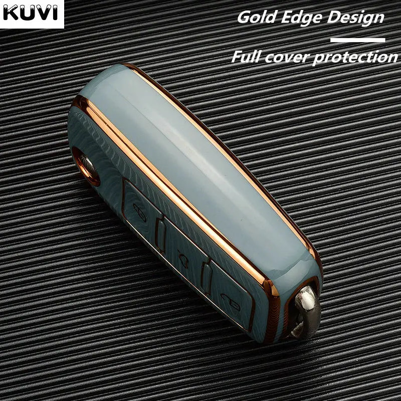 A close-up of a light blue TPU car key cover with a gold edge design placed on a black textured surface.