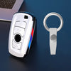 Un juego de funda para llave de coche plateada con un llavero y una funda protectora, colocado sobre una superficie azul oscu