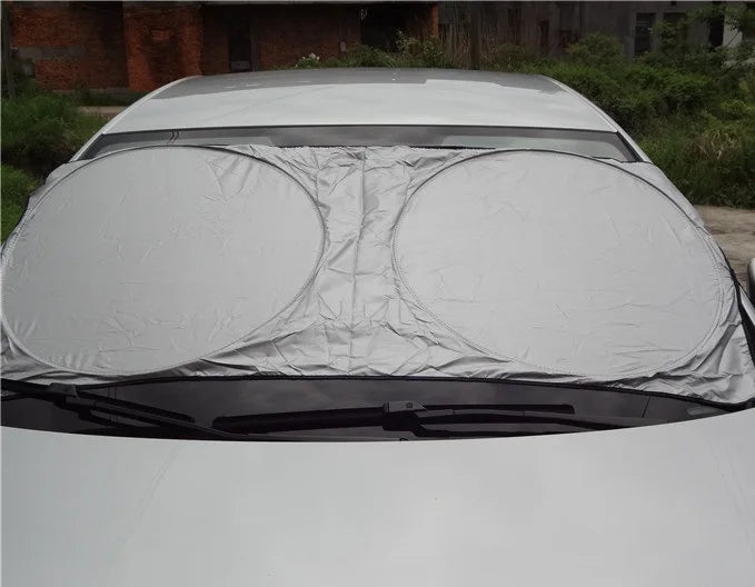 A white folding car sunshade is shown covering the windshield of a vehicle.