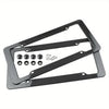 Black carbon fiber license plate frame with mounting hardware for a vehicle.