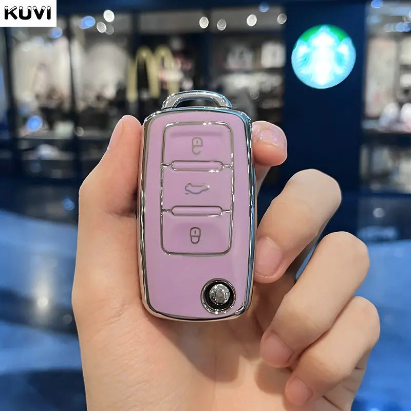 A hand holds a pink TPU car key cover with multiple buttons and a silver keyring.
