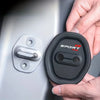A hand holds a black car door lock protector set with a silver latch, showing the mechanism for universal car door locks.